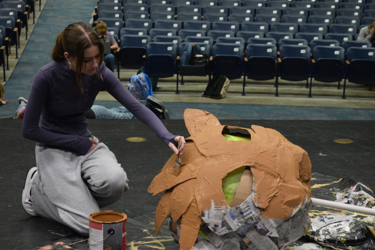 A drama student paints the head of the Lion that will be featured in the play. 